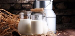 Una jarra de leche y un vaso de leche sobre una mesa de madera